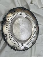 Top view of silver-plated decorative tray showing pierced rim and engraved center