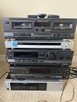 Stacked components including cassette deck on top, silver Sony DVD/CD player, Technics amp/receiver, Zenith CD changer and LG video recorder at bottom