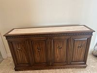 Front view of traditional brown wooden sideboard with four doors and brass ring pull handles.