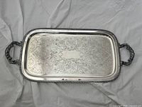 Top view of rectangular silver plated tray showing ornate engraved floral design and decorative rope edge with curved handles on each side.