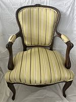 Front view showing yellow striped upholstery and carved wooden frame with padded arms and legs.