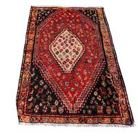 Photo of the full rug showing the central diamond medallion pattern in red, black, and cream colors, with floral and geometric motifs.