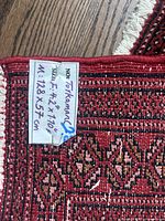 Close-up of the woven label showing size and origin: Size 4.2 x 1.10 ft (128 x 37 cm), identified as a Turkmen rug.