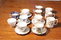 Photo showing all 10 cups with matching saucers arranged on wooden surface, various floral patterns visible