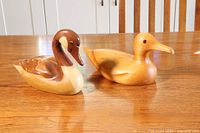 Two wooden duck decoys on a wood table, showing overall appearance and relative sizes