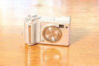 Front view of silver Fuji Finepix E500 camera with lens closed, showing compact body and grip.