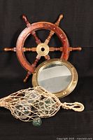 Full lot view showing all nautical items: ship's wheel, porthole mirror, and glass floats in net.