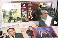 Photo showing nine vintage LP records with covers including comedy and classical music artists like Bob & Doug McKenzie, Bob Newhart, Lily Tomlin, and classical orchestra.