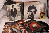 Photo showing assortment of LP album covers including Bruce Cockburn, Elvis Presley, Gino Vannelli, The Moody Blues, and others with records partially visible.
