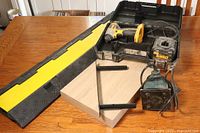 Full lot image showing DeWalt drill in case, floating shelf, sander and cord cover on a wooden table.