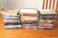 Three stacks of DVDs on a wooden desktop, showing a variety of titles including Stargate SG1, Revenge, Crusade, and Red Skelton among others.