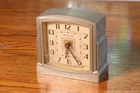 Front angled view showing the full clock face, metal body, and small chip on glass's lower left corner.