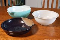 Two vintage Pyrex bowls and one ceramic serving tray placed on wooden table