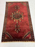 Full view of the Ferdos Persian rug showing overall design and coloration on a grey floor.