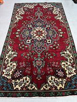 Full view of the Tabriz Persian rug showing vibrant red field, central medallion, and green borders.