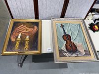 Both framed paintings displayed side by side on a table showing overall condition and appearance.