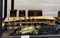 Brass decorative coat hooks, mother of pearl towel rail, black metal hooks, and other fixtures displayed on shelving