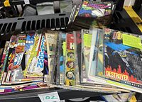 Stack of assorted comic books including superhero titles from Marvel and DC, some in protective sleeves