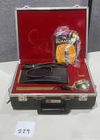 Red-lined hard carrying case with leather strap Polaroid camera, metal flash reflector, and sealed batteries