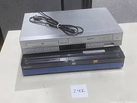 Sony Blu-Ray player stacked under Toshiba VHS/DVD combo player showing front panels and power cord on top.