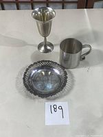 Three items on tabletop: coaster at front, pewter goblet and tankard behind
