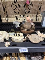 Overview of assorted small figures on black shelf, includes wooden carved panel background