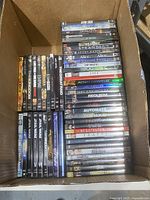 Box of assorted used DVDs showing titles such as Star Trek, Serenity, Sunshine, Alice, The Fog, Mutant Chronicles, Melancholia, Requiem, Automata, The Negotiator, The Great Raid.
