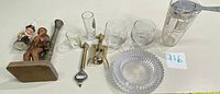 Overall lot arranged showing all items including hand carved wooden figure bottle opener, brass openers, mixing glass, porcelain toothpick holder, crystal ashtray, bar and shot glasses