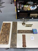 All items displayed on white table showing wooden cookie molds, brass menorahs, 'Shalom' piece, candle box, and wooden carved leaf.
