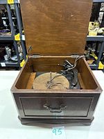 Vintage General Electric turntable inside wooden case with lid open showing turntable platter, tonearm, and wiring.