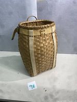 Full view of vintage woven trappers basket standing upright showing its shape and weave pattern