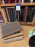 View of 8 coffee table books, including three volumes of The Canadian Encyclopedia and other assorted titles on shelves.