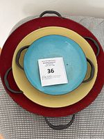 Top view of the nested enamel bowls showing red, yellow, and blue enamel surfaces and black handles