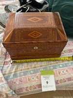 Front and side view of the handmade wooden box showing the detailed inlay design and keyhole on the front.