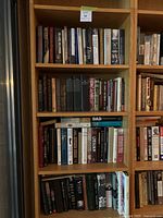 Books on wooden shelves showing titles related to history, politics, arts, and biographies. Shelf tagged with lot number 54.