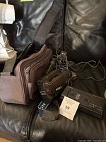 Sony CCD-FX310 NTSC camcorder with charger and brown carrying case placed on a black leather couch.