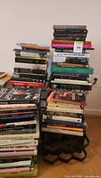 Full view of multiple stacks of books arranged on floor showing titles and spine details, featuring art, architecture, music, and fashion themed volumes.