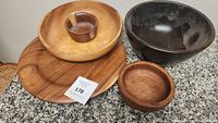 Four wooden bowls arranged closely, showing different wood tones and sizes, some with dust and signs of use.