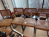 Four rattan cane and metal dining chairs in a row, front view