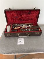 Opened case showing vintage wooden clarinet disassembled into parts inside red velvet lining with accessories