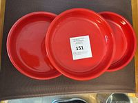 Set of four red round shallow bowls with label number on top bowl.