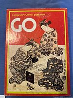 Outer box front art showing 2 traditional Japanese women playing Go, with text 'the legendary Oriental game of skill GO'