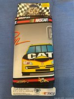 Rolled and packaged NASCAR wallpaper border with Caterpillar CAT logo on NASCAR race car, showing size and branding.