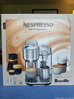 Front of sealed retail box showing Nespresso Vertuo Creatista machine image, Breville branding, and note x1 machine x12 capsules