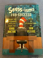 Front cover of the book titled 'Seuss-isms For Success' showing an office chair, red and white striped hat, and cityscape background.
