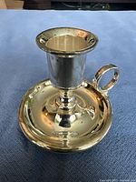 Front and top view of shiny silverplated candle holder with circular base and handle.