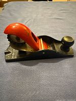 Side view of block plane showing red handle, body, knob, and blade adjustment