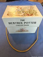 Photo of the light blue box with The Beatrix Potter Collection title and gold rope handle, showing top and side illustrations of characters.