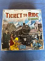 Front cover of the Ticket to Ride Europe board game box showing illustrated artwork of a steam train and passengers in period attire.