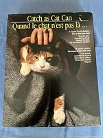 Front box cover of Waddingtons Catch As Cat Can puzzle mystery game showing image of a cat being held by two hands and bilingual English and French text.